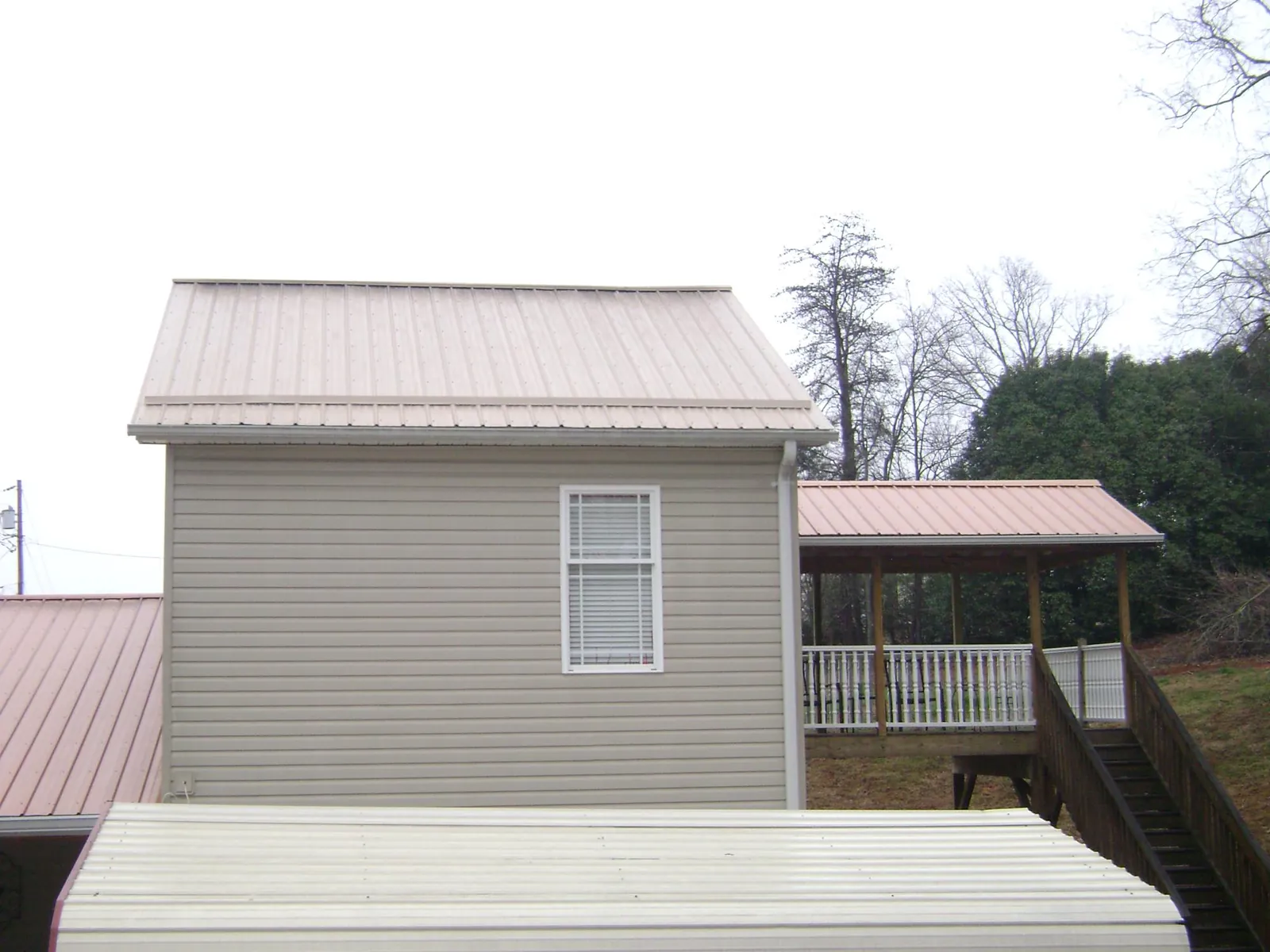 Tan metal roofs on a two story addition and attached porch, from a Roof Replacement job in Richboro