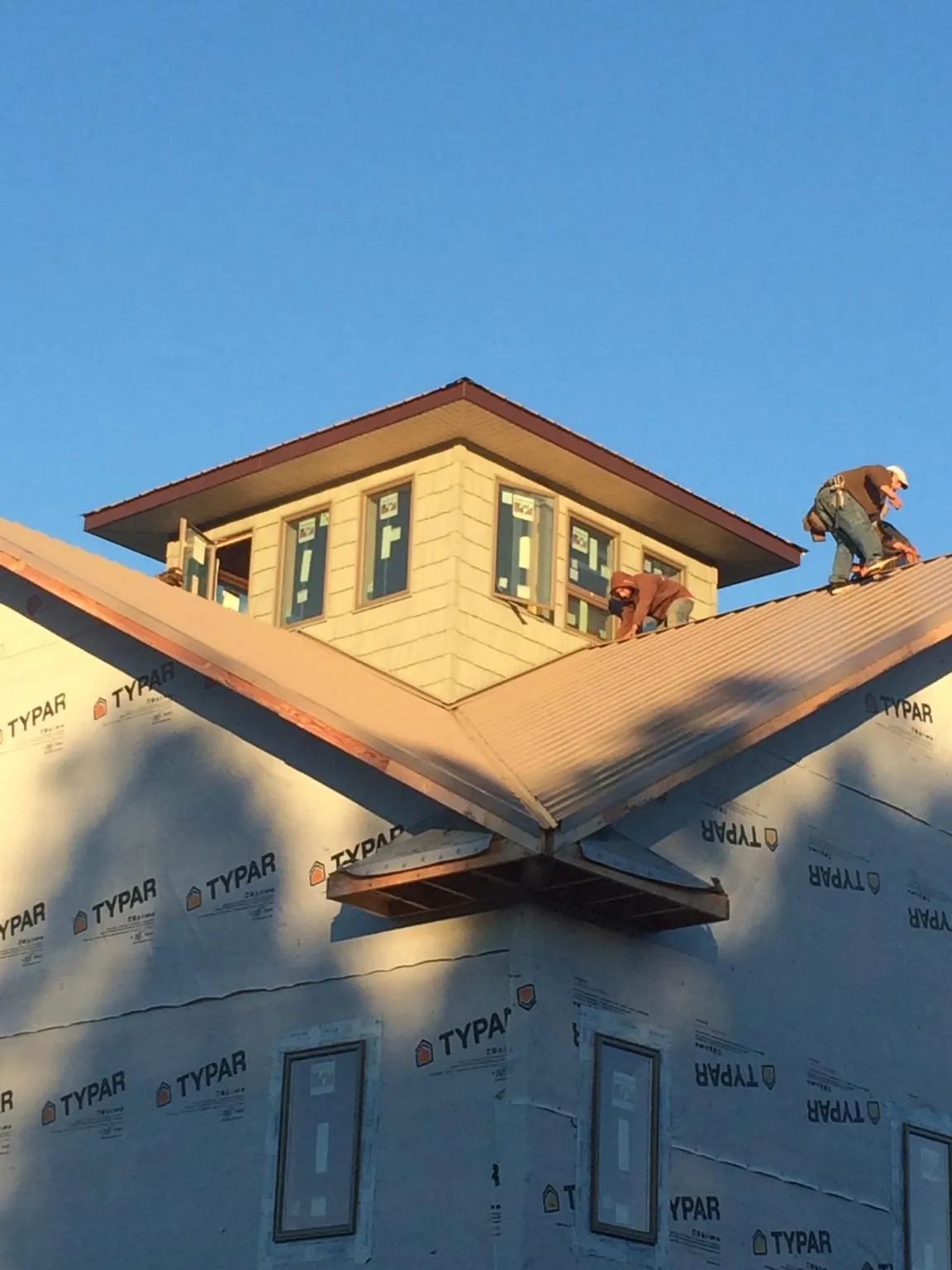 Roofers working around a rooftop cupola on a new metal roof at sunset — Roof Waterproofing in Richboro by Roofing Brothers